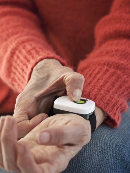 Ältere Person betätigt Alarmknopf am Handgelenk