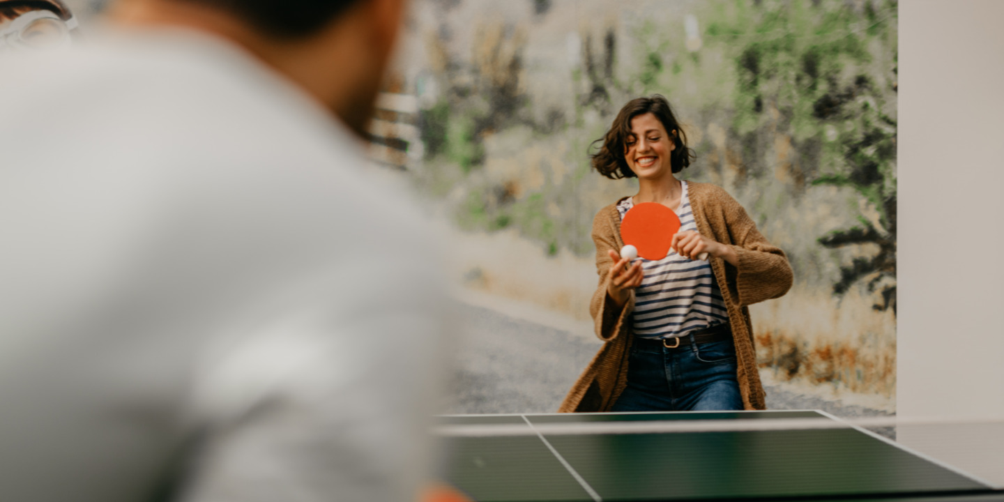 Lachende Frau spielt Tischtennis