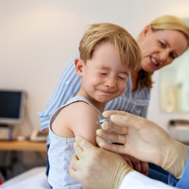 Junge erhält beim Kinderarzt eine Impfung in den Arm