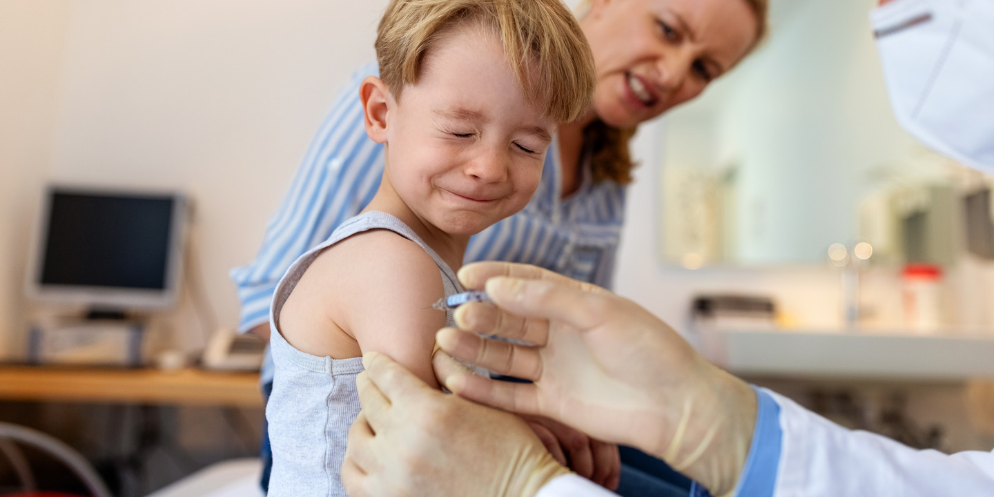 Junge schliesst während der Impfung die Augen beim Hausarzt