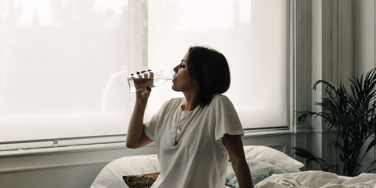 Frau trinkt Wasser am Morgen nach dem Aufstehen