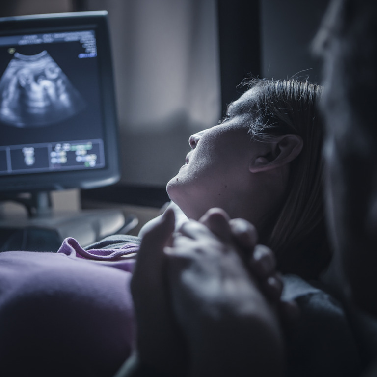 Frau blickt auf Ultraschallbild