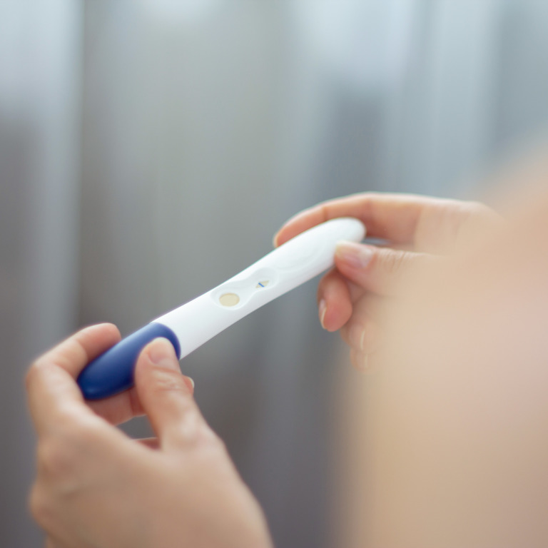 Frau hält einen Schwangerschaftstest in den Händen