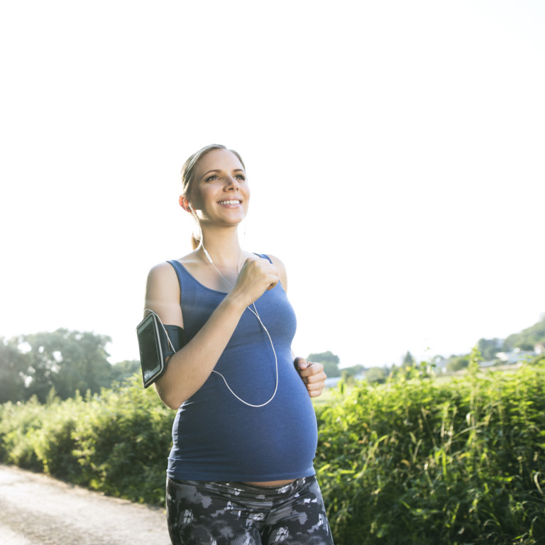 schwangere Frau joggt auf einem Feldweg