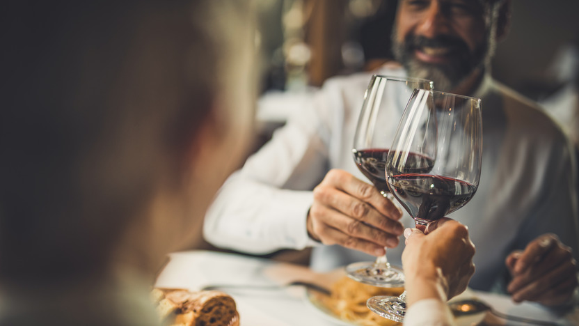 Pärchen stoßt beim Abendessen im Restaurant mit Rotwein an