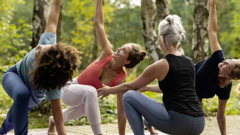 Drei Frauen machen Yoga mit einer Trainerin