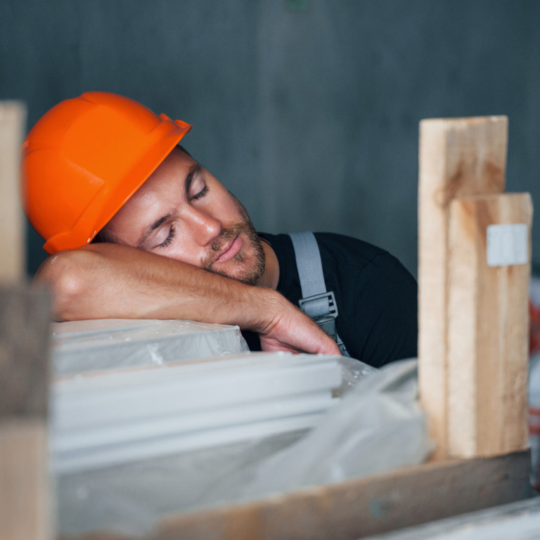 Handwerker mit Helm macht Mittagsschlaf