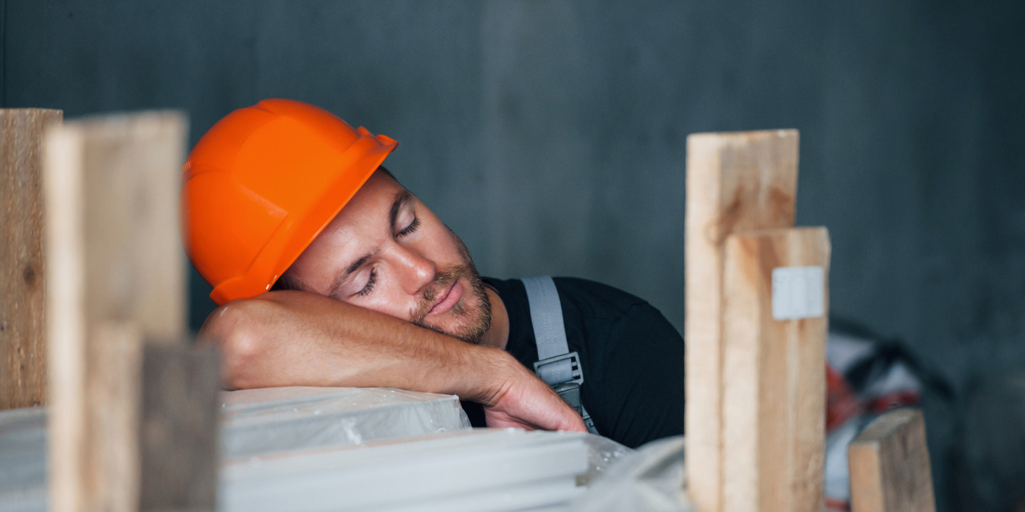 Handwerker mit Helm macht Mittagsschlaf