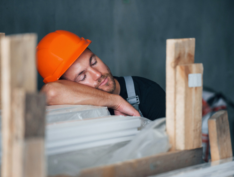 Handwerker mit Helm macht Mittagsschlaf