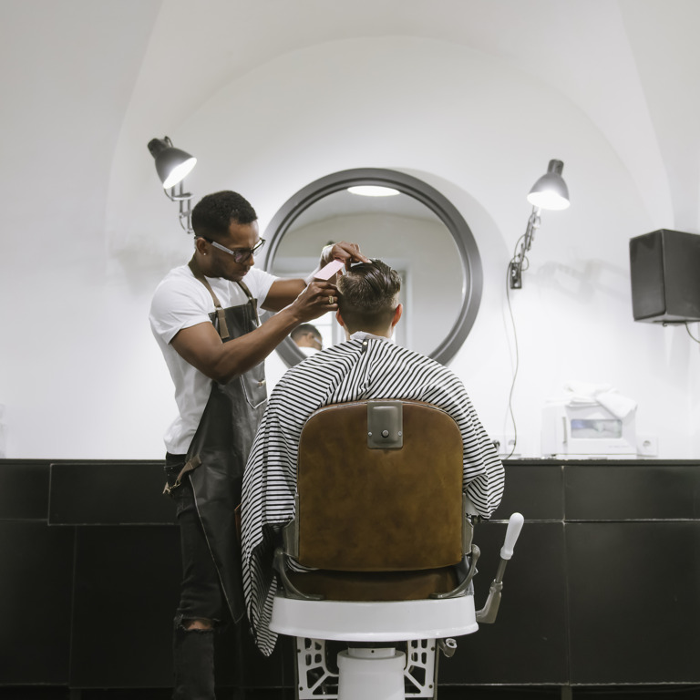 Junger Friseur schneidet einem Kunden die Haare