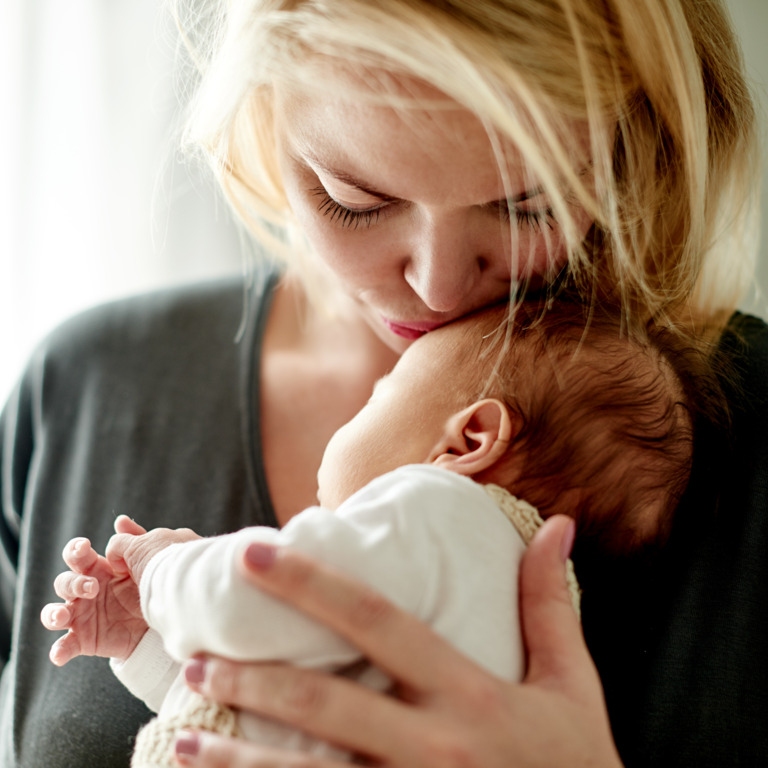 Mutter gibt ihrem Baby Kuss auf den Kopf