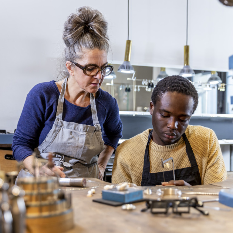 Ausbilderin erklärt einem jungen Migranten eine Arbeitstechnik