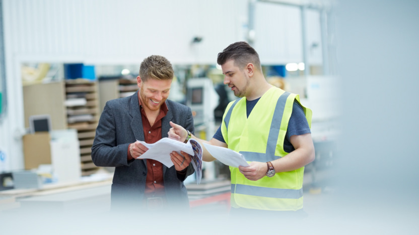 Handwerker und Vorgesetzter gehen gemeinsam Unterlagen durch