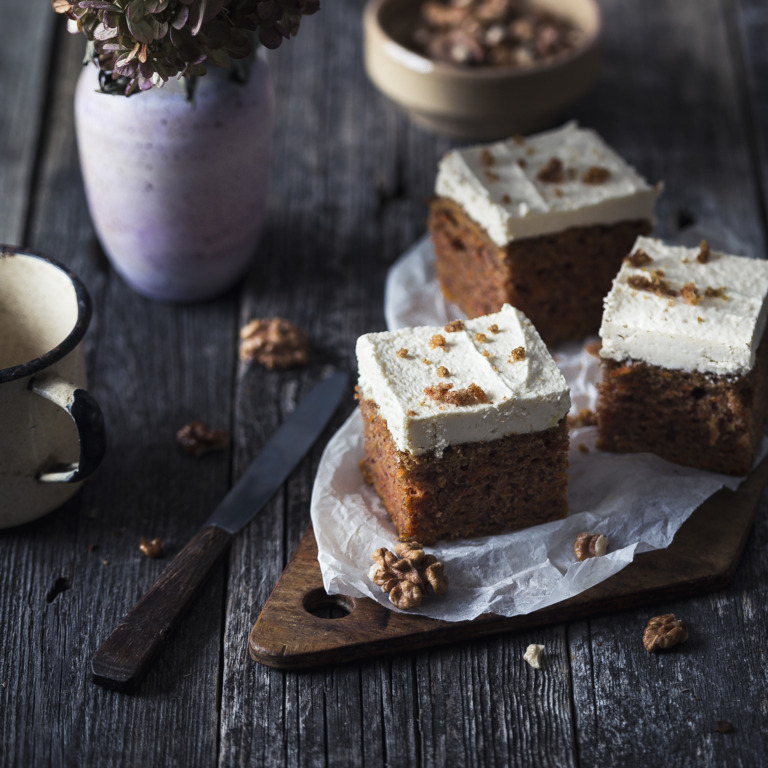 Drei Stück Karottenkuchen auf einem mit Blumen dekorierten Tisch