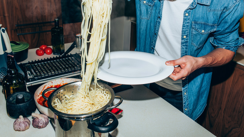 Student nimmt sich eine Portion Spaghetti aus einem Topf