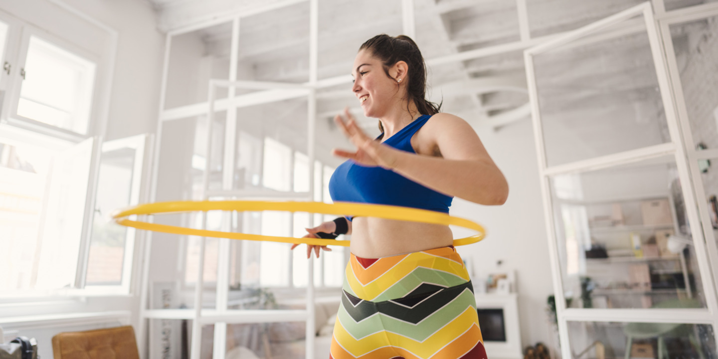 junge Frau liegt ganz im Trend und treibt Sport mit einem Hula-Hoop-Reifen