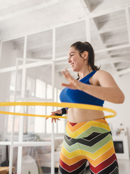 junge Frau liegt ganz im Trend und treibt Sport mit einem Hula-Hoop-Reifen