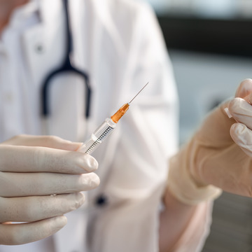Arzt hält eine mit einer Impfdosis gefüllte Spritze in der Hand