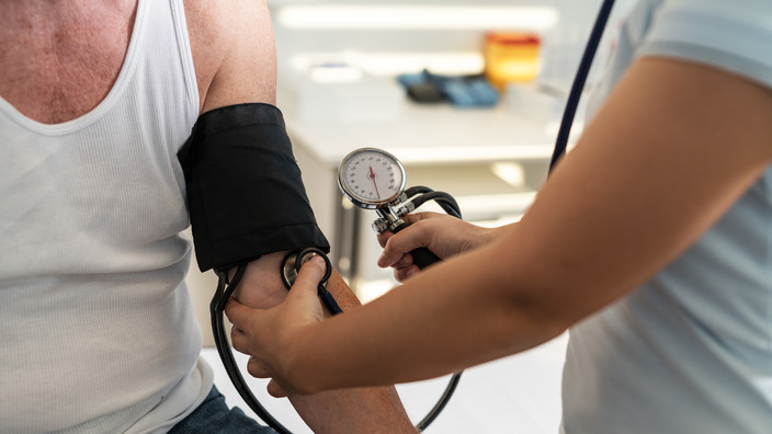 Ärztin misst den Blutdruck eines Patienten