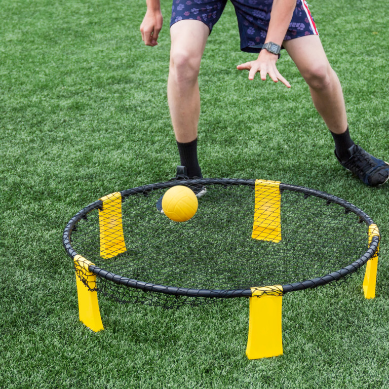 Person spielt Spikeball auf dem Rasen