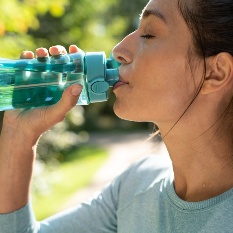 Joggerin trinkt während einer Pause Wasser aus einer Trinkflasche