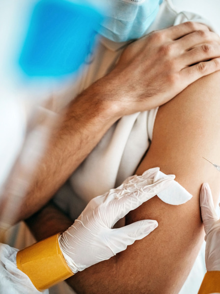 Mann bekommt durch einen Arzt eine Corona-Impfung in den Arm