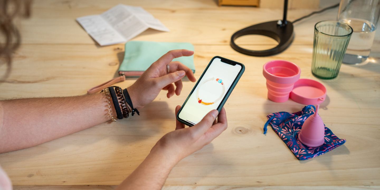 Frau benutzt eine Zyklus-App auf ihrem Handy 