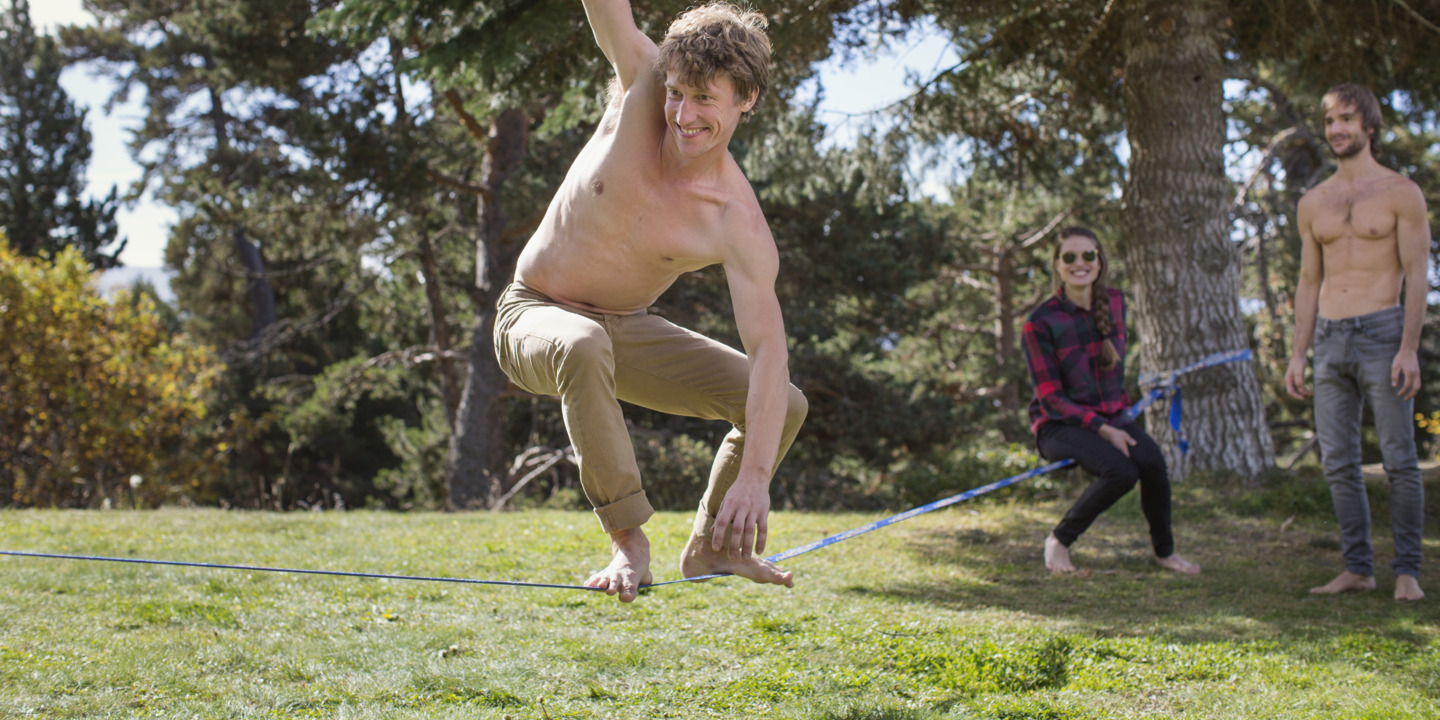 junger Mann balanciert auf einer Slackline