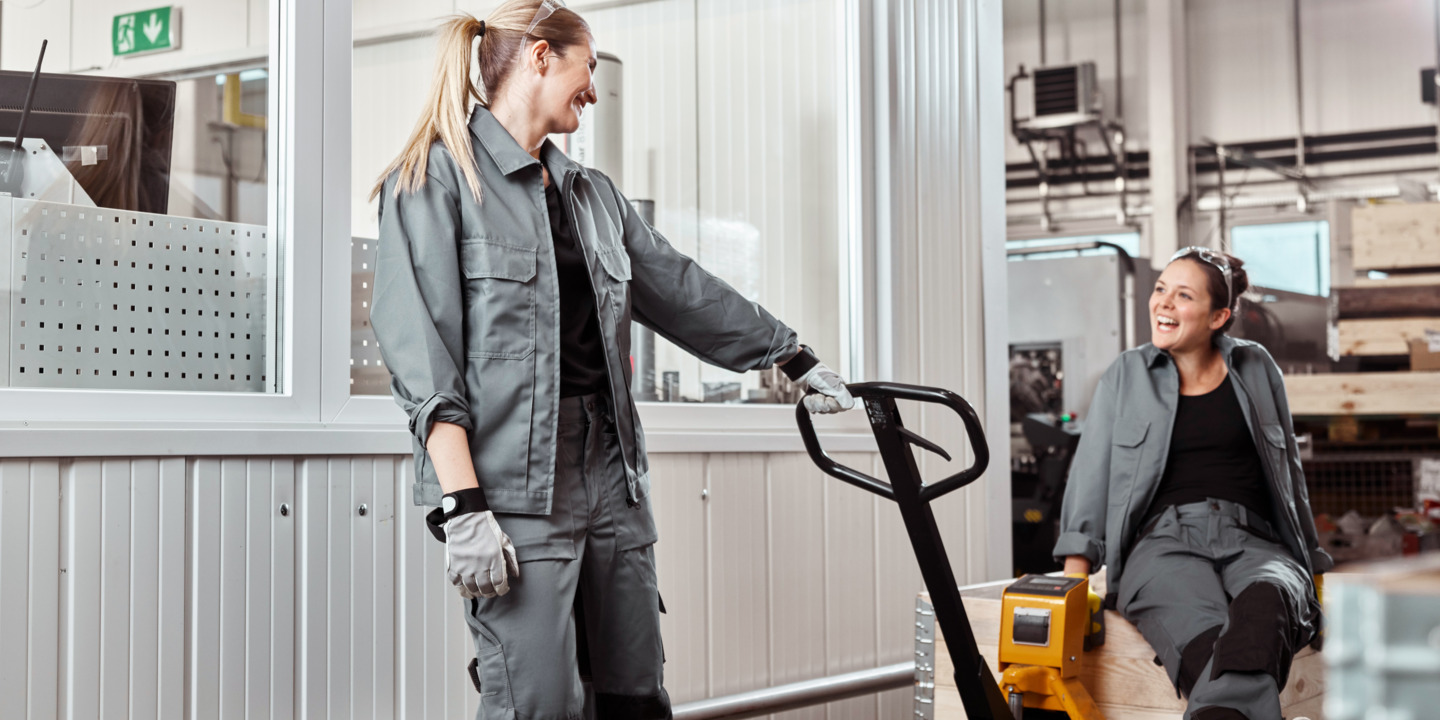 Zwei Frauen arbeiten zusammen in Lagerhalle.