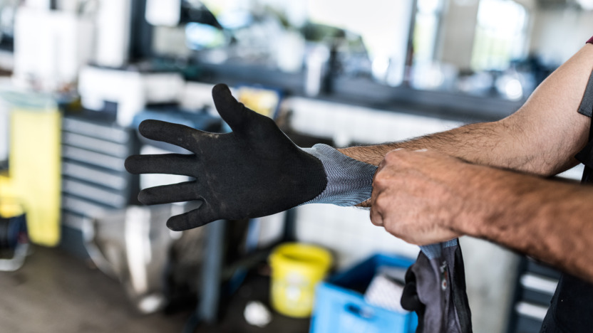 Mann streift sich einen Arbeitshandschuh über