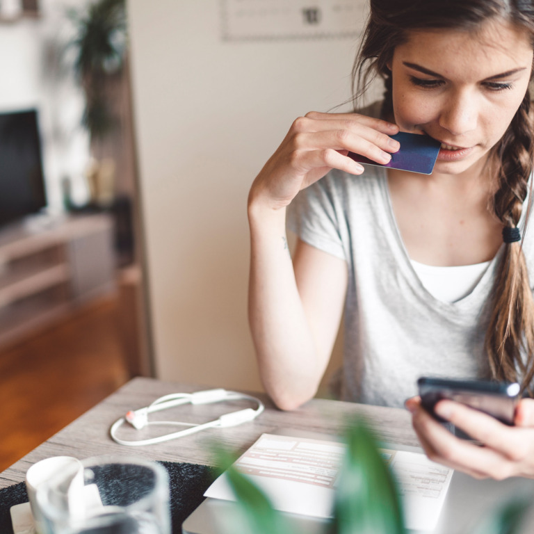 Junge Frau schaut auf ihr Smartphone.