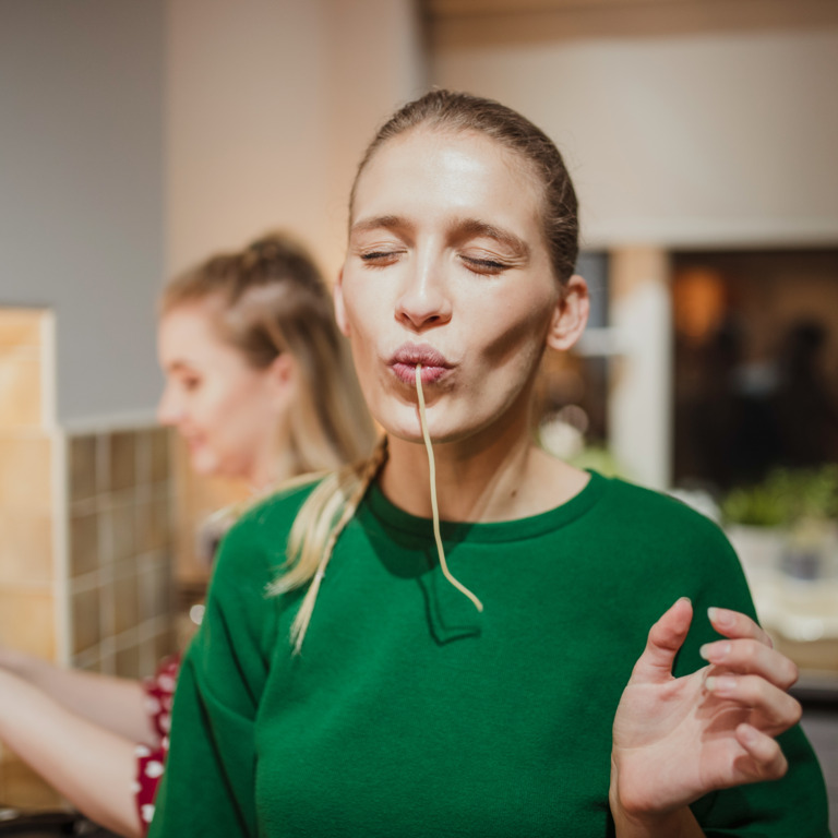 Frau genießt eine Spaghetti beim Kochen in der Küche.