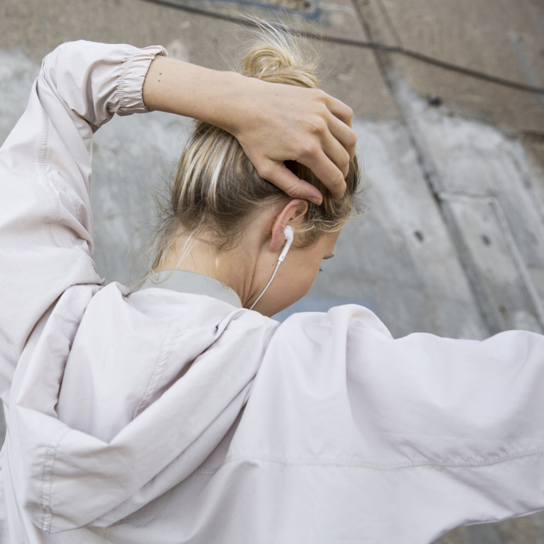 Junge Frau macht eine tanzende Bewegung und hört über Kopfhörer Musik.