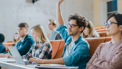 Studentinnen und Studenten sitzen im Hörsaal und melden sich