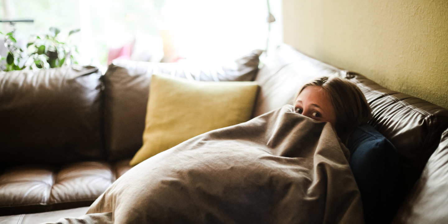 Junge Frau versteckt sich unter einer Decke