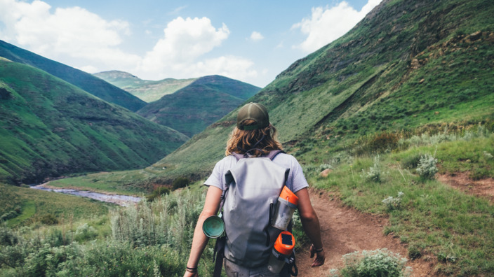 sportlicher junger Mann wandert mit dem Rucksack durch eine Berglandschaft