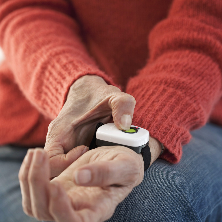 Ältere Person betätigt Alarmknopf am Handgelenk