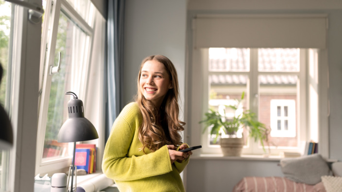 Eine junge Frau schaut aus dem Fenster.