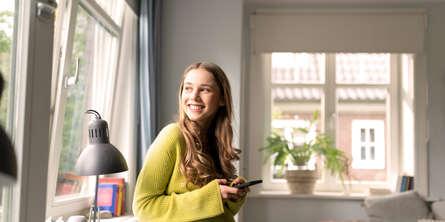 Junge Frau schaut neugierig aus dem Fenster