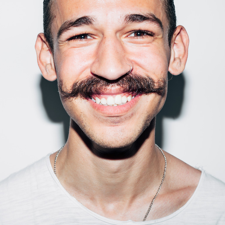 lächelnder junger Mann mit einem großen Schnurrbart