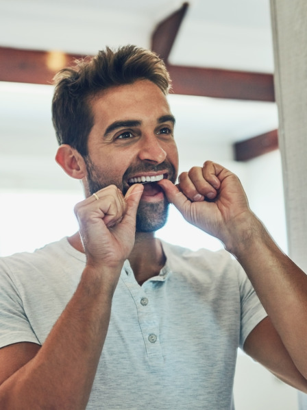 Mann pflegt seine Zähne mit Zahnseide