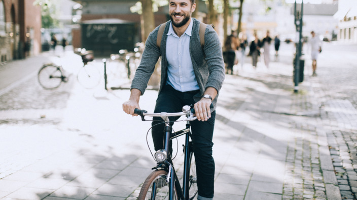 Mann mit Rucksack fährt mit dem Fahrrad durch die Stadt