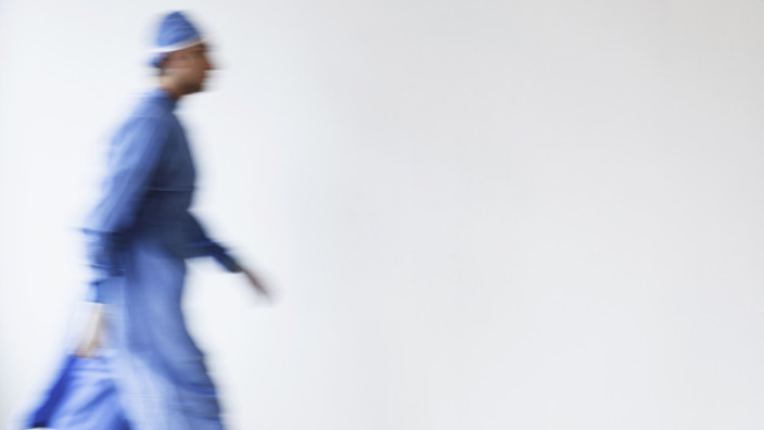 Arzt in OP-Kleidung eilt einen Flur entlang