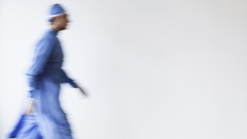 Arzt in OP-Kleidung in Unschärfe läuft über einen Gang