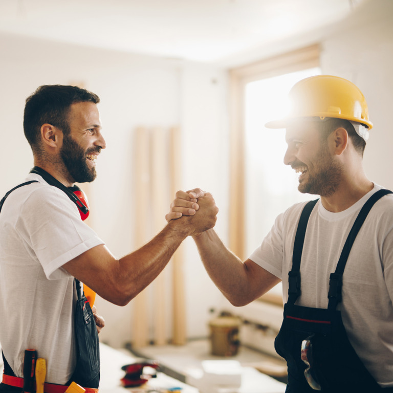zwei Bauarbeiter begrüßen sich auf einer Baustelle