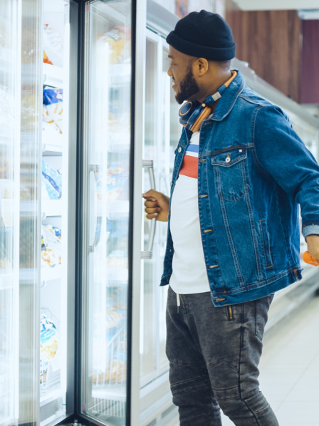 Mann mit Einkaufswagen steht vor Regal im Supermarkt