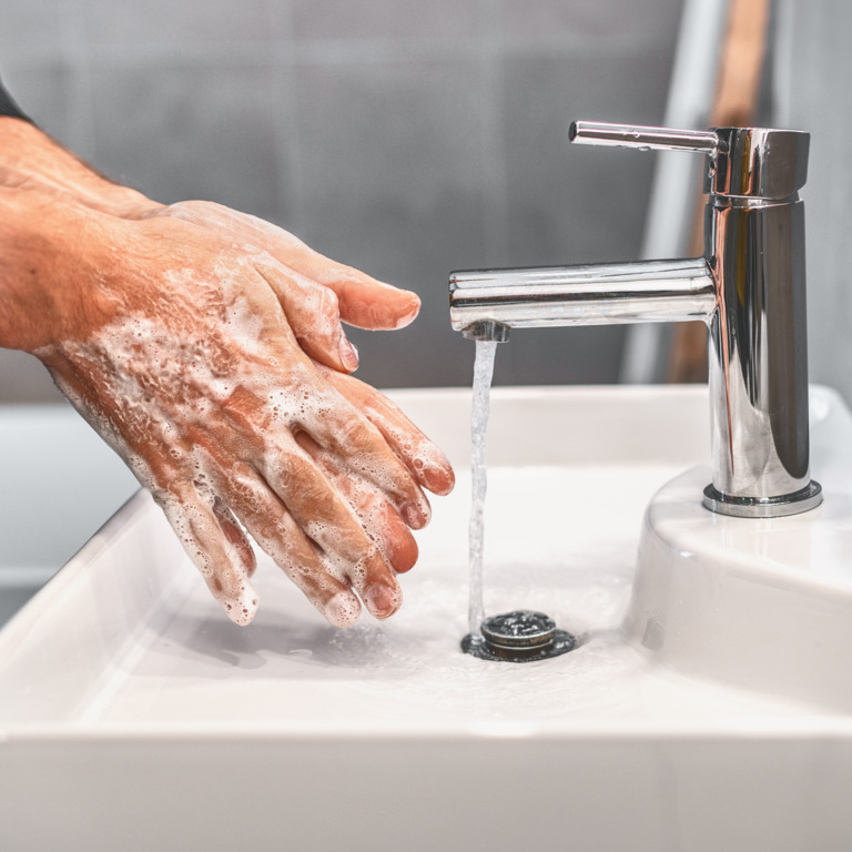 Eingeseifte Hände über einem Waschbecken.