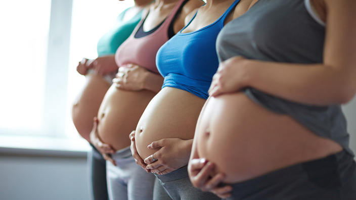 vier Schwangere stehen nebeneinander und zeigen ihren Bauch
