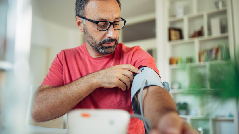 Mann misst den Blutdruck mithilfe eines Messgeräts