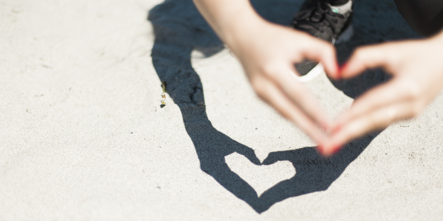 Frau formt mit ihren Fingern ein Herz